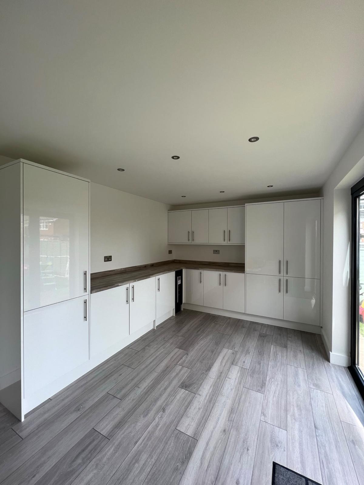 Interior with fitted white cabinets and wood-effect flooring